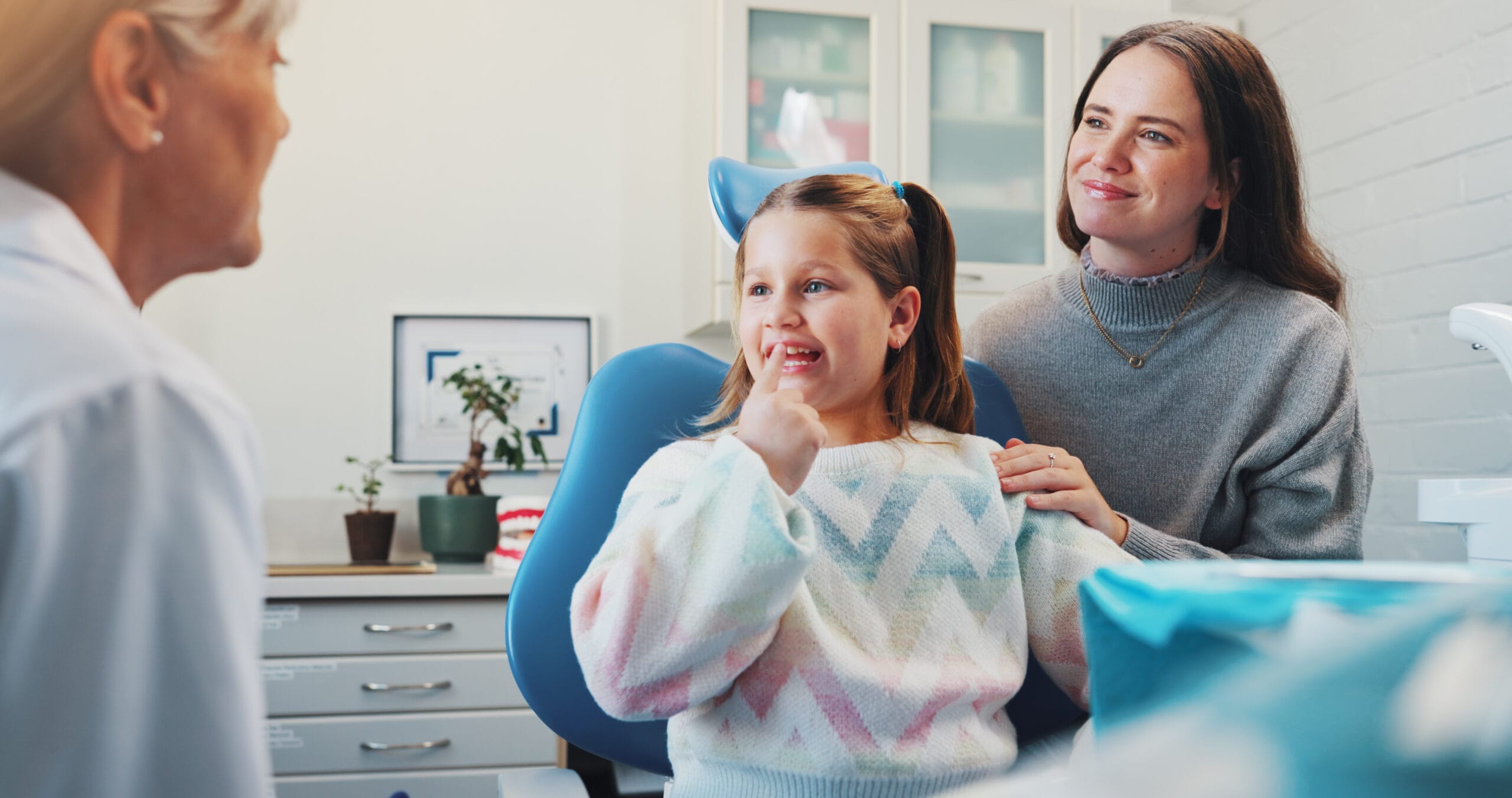 Child, dentist and show tooth at dental consultation with orthodontist for advice or cleaning. Happy girl, family or woman in clinic for gum care, wellness and learning about oral hygiene and health Children’s Dentistry Sarnia